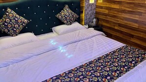 A neatly made bed with a floral-patterned bedspread and two decorative pillows. - The Heritage Safina Group Of Houseboats (Srinagar)