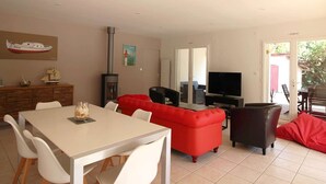 Ein Wohnzimmer mit einem weißen Tisch, einem roten Sofa und einem Fernseher.
