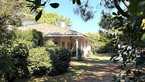 Ein Haus mit Ziegeldach, umgeben von üppiger Vegetation und einem Kiesweg.