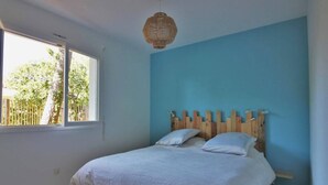 Ein Schlafzimmer mit einem großen Bett, einem hölzernen Kopfteil, einem Fenster und einer Pendelleuchte.