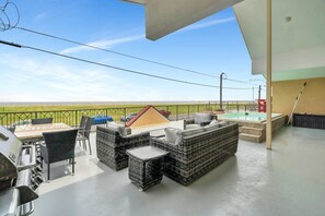 A rooftop patio with outdoor furniture, a barbecue grill, and a pool.