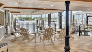 Un espace extérieur aménagé, abrité et doté de chaises Adirondack, offrant une vue sur le port de plaisance.