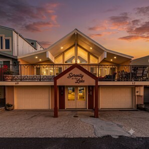 A building with a sign reading 'Serenity at the Lake' with a covered entrance and a balcony.