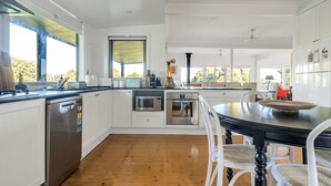Een moderne keuken met witte kastjes, roestvrijstalen apparatuur en een houten vloer.