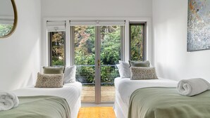 Een kamer met twee bedden, een groot raam en uitzicht op groen.