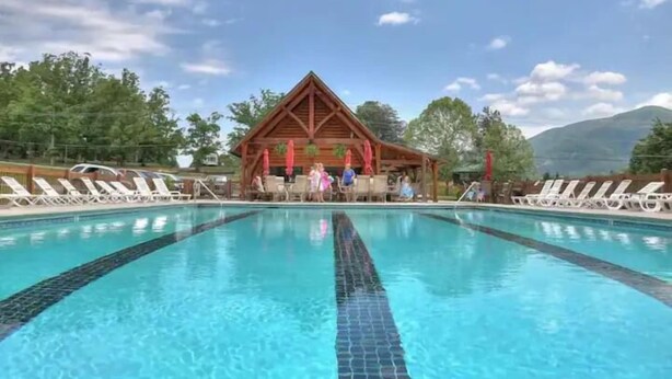 A swimming pool with lounge chairs and a wooden pavilion in the background. - KunTree Retreat by Beyond Expectations: Pet-Friendly w/ Hot Tub, Sauna & Firepit (Sevierville)