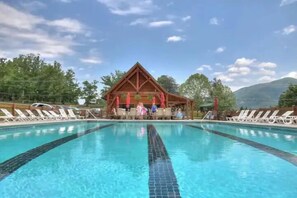 A swimming pool with lounge chairs and a wooden pavilion in the background. - 3BR Cozy Sevierville Cabin w/ Hot Tub, Fire Pit, Sauna, Theater + Game Room (Sevierville)