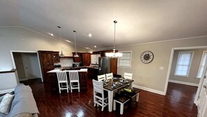 A spacious living area with hardwood flooring, a dining table with chairs, a kitchen with wooden cabinets, and a chandelier. - KunTree Retreat by Beyond Expectations: Pet-Friendly w/ Hot Tub, Sauna & Firepit (Sevierville)