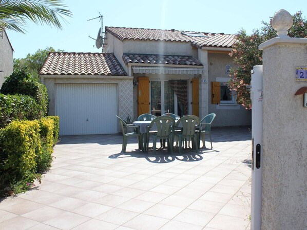 A residential property with a tiled patio, a dining area with outdoor furniture, and a garage. - Spacious 3-Room Villa with Mezzanine, Terrace & BBQ, Near Grazel Beach - Sleeps 6 (Gruissan)