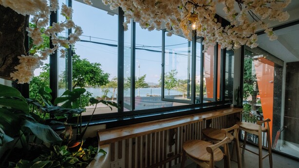 A modern interior with large windows, wooden bar counter, and indoor plants. - La Beaute Hotel Quy Nhon (Quy Nhon)
