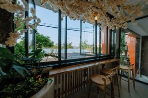 A modern interior with large windows, wooden bar counter, and indoor plants.