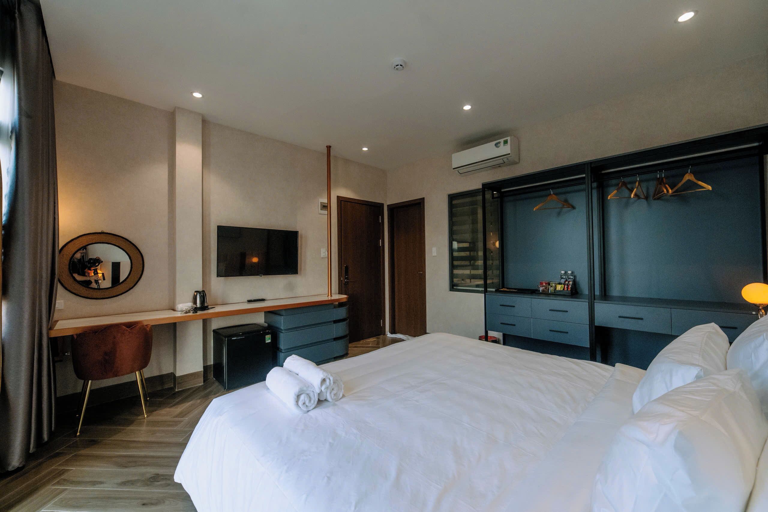 Ein Hotelzimmer mit einem großen Bett, einem Schreibtisch mit Stuhl, einem Fernseher, einem Kleiderschrank und einem Spiegel.