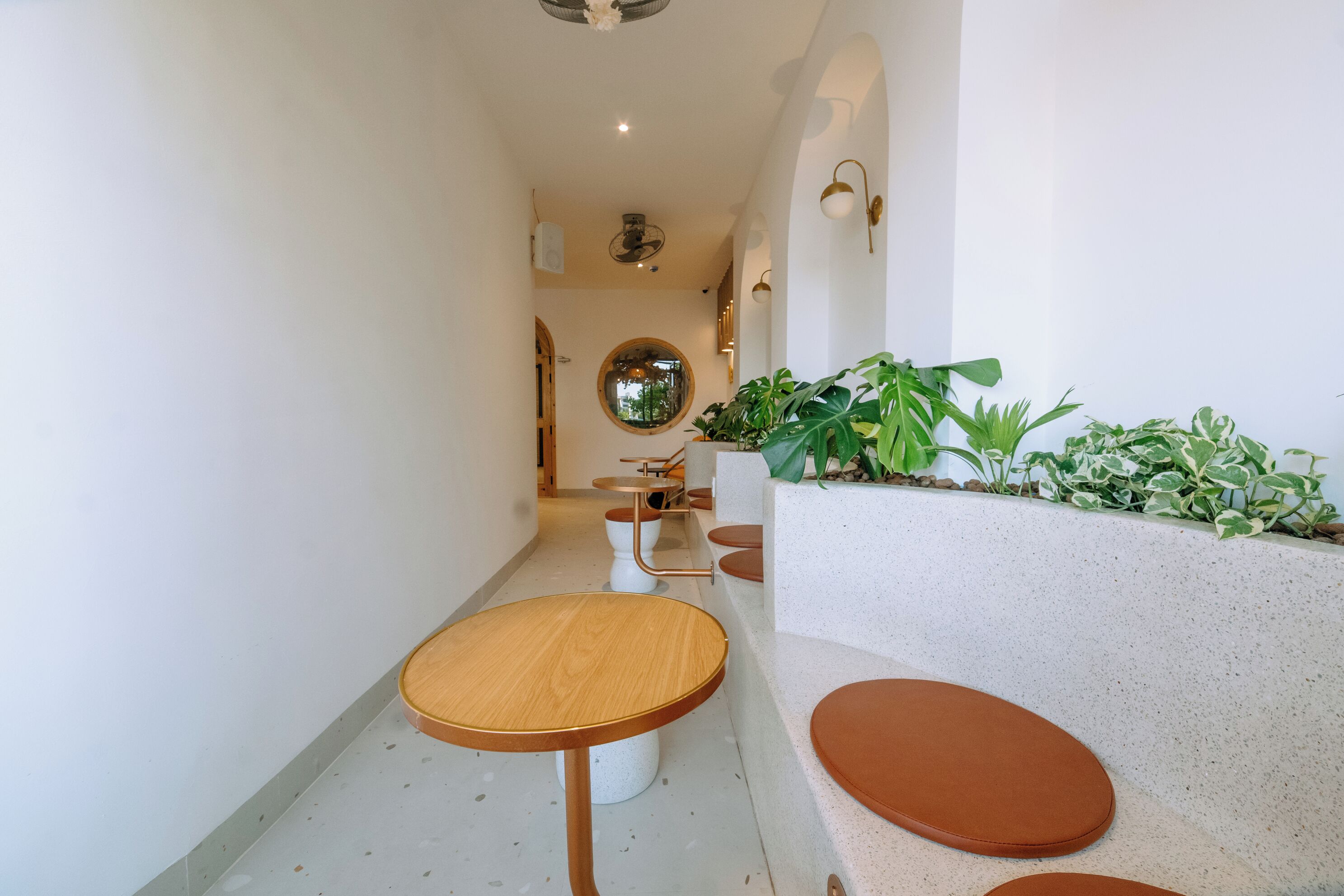 A narrow hallway with a round wooden table and two cushioned seating areas.