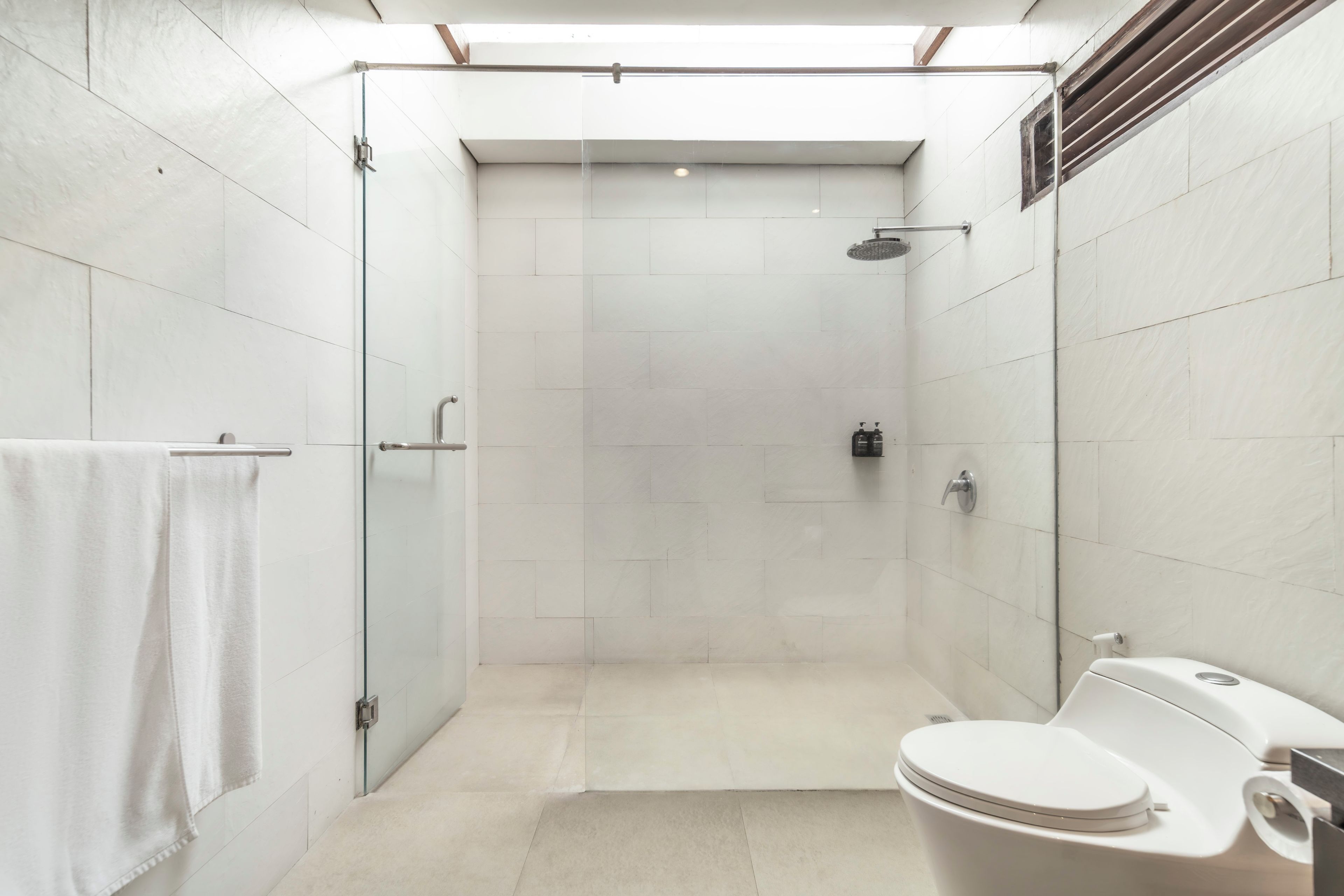 A modern bathroom with a glass shower enclosure, a toilet, and a sink.
