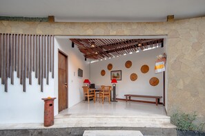 A modern dining area with a stone wall, wooden slats, and a bench.