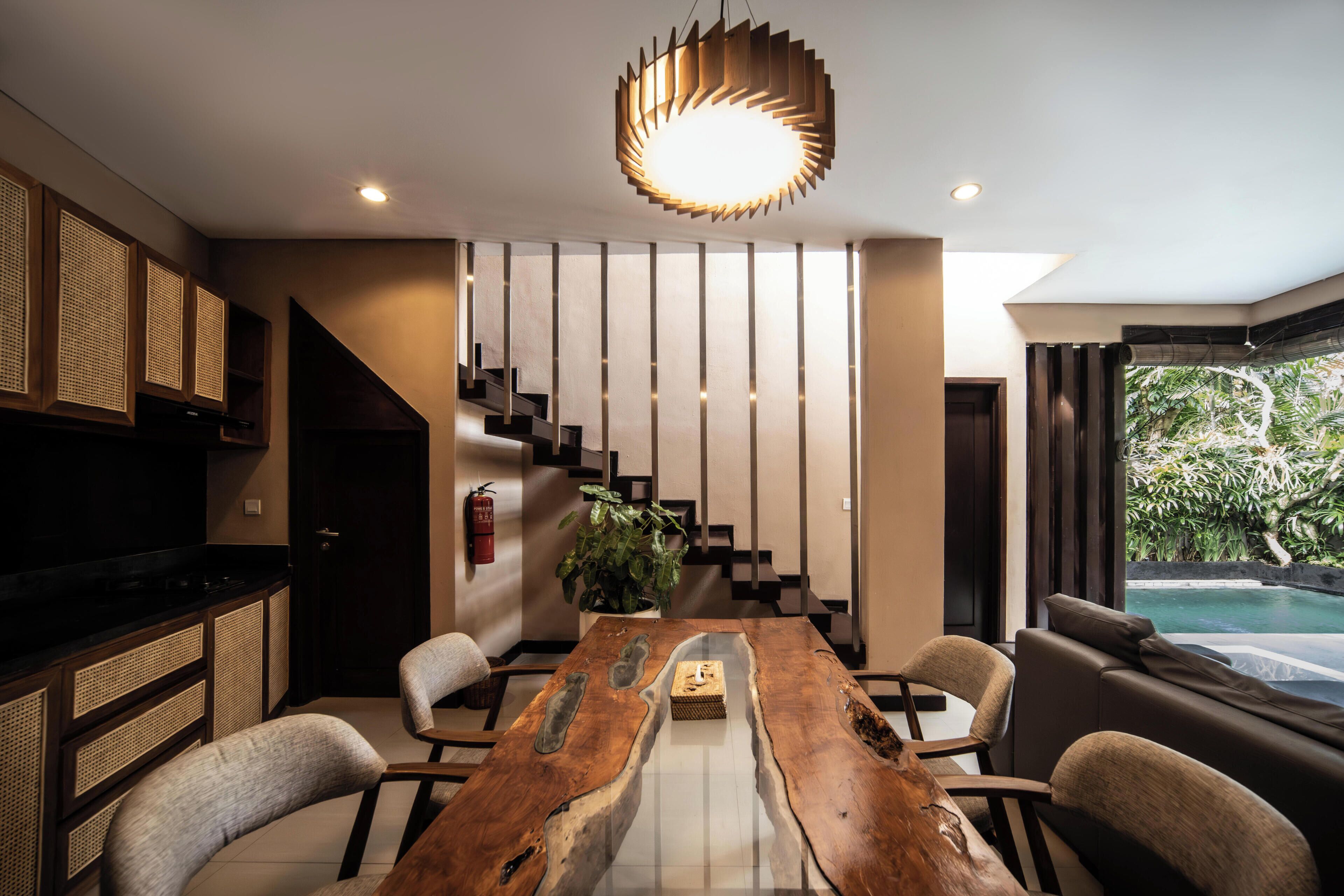 Un interior moderno con una mesa de comedor de madera, sillas, una escalera, un televisor y vistas a una piscina.
