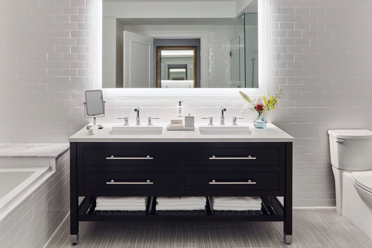 A modern bathroom with a double sink vanity, a large mirror, and a toilet.