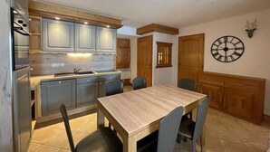 Une cuisine avec une table et des chaises en bois, une horloge au mur et des placards.