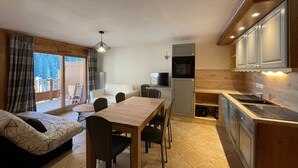 Un espace de vie compact comprenant un coin repas, une kitchenette et un canapé.