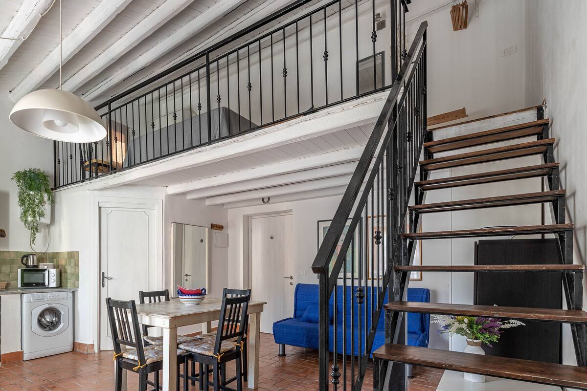 A multi-level apartment with a dining area, kitchen, and a staircase.