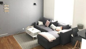 Una sala moderna con un sofá gris, una mesa de centro blanca y una alfombra estampada.