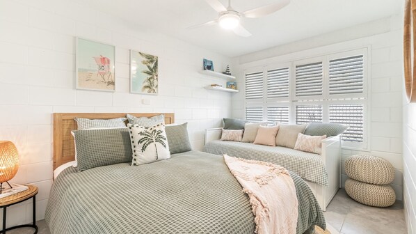 Une chambre à coucher avec un lit, un banc et une fenêtre équipée de stores.