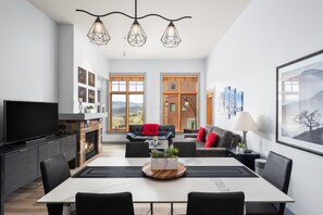 Un salon moderne avec une cheminée, un coin repas et un téléviseur.