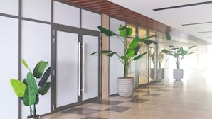 Un couloir moderne avec des portes en verre, des plantes en pot et un sol à carreaux.