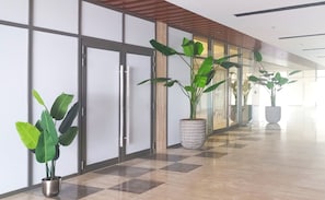 Enter a clean and welcoming space with a checkered floor, lush greenery, and sleek glass doors.