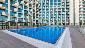 Un bâtiment moderne doté d’une piscine sur le toit, entouré d’un immeuble résidentiel de grande hauteur.