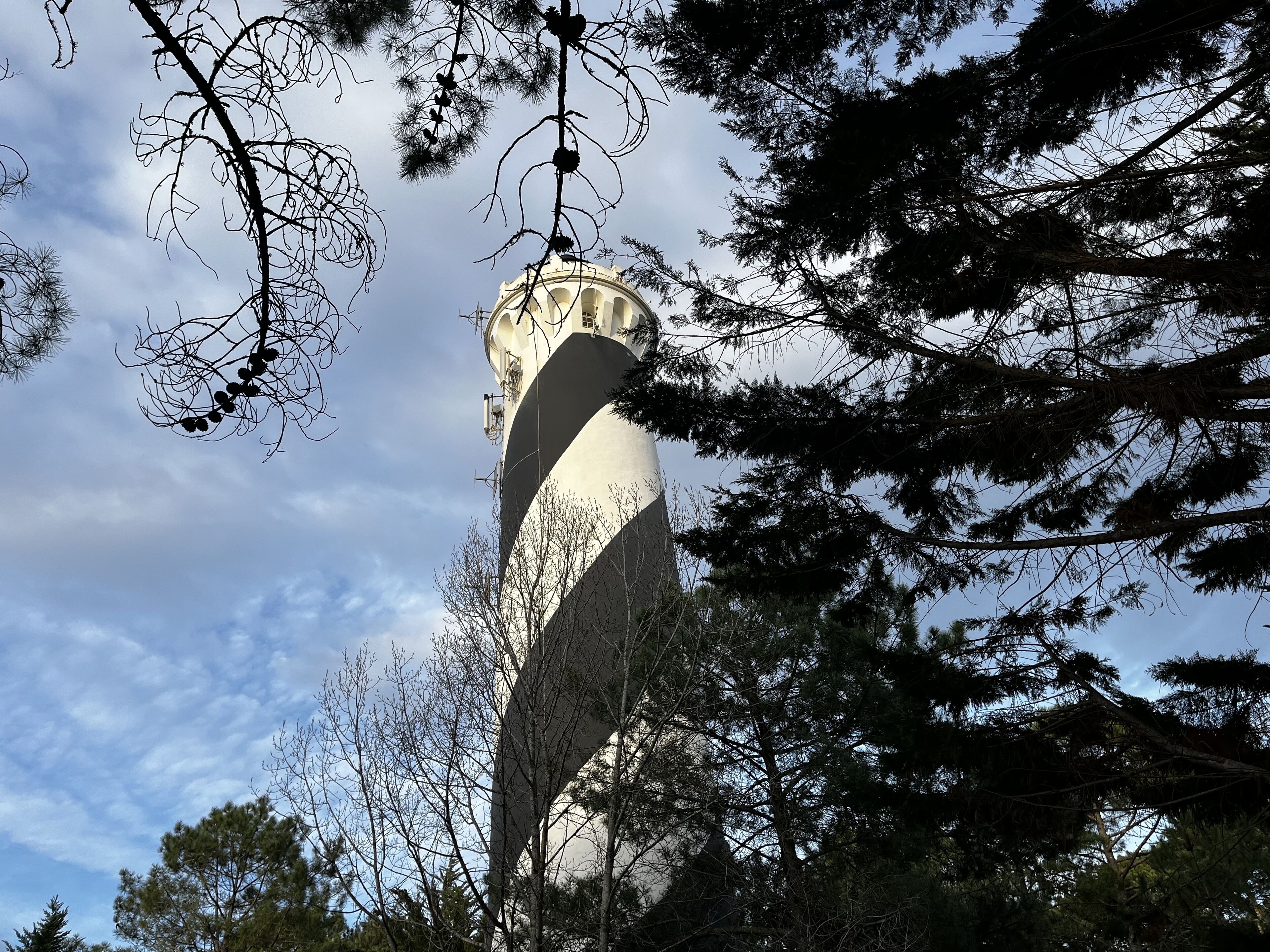 A tower with a clock, surrounded by trees and a clear sky.
