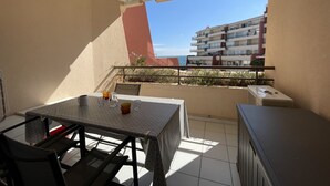 A balcony with a table and chairs, a view of a building, and an air conditioning unit. - Seafront apartment for 4 in Sète with private parking (Sète)