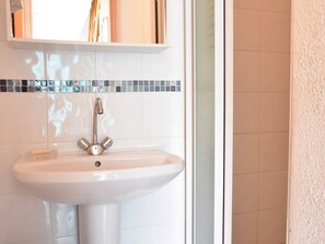 Une salle de bain avec un lavabo blanc, un robinet chromé et un miroir au-dessus.