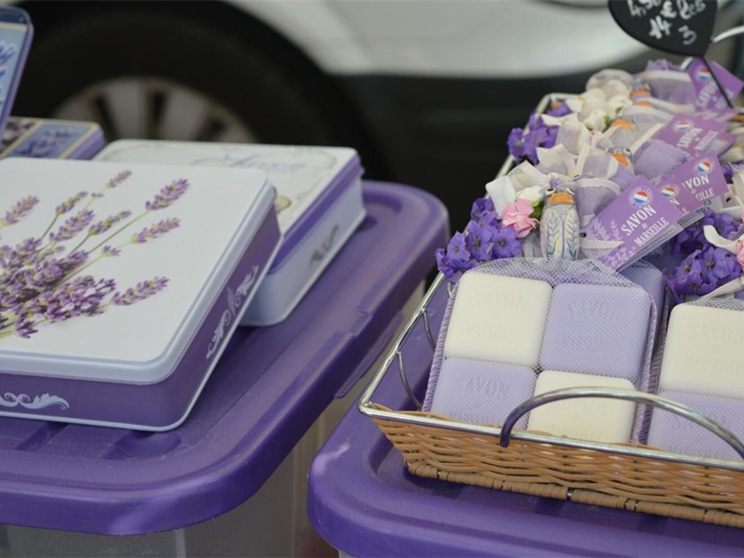 Lavender-scented soap bars in a basket and boxes on a purple table.