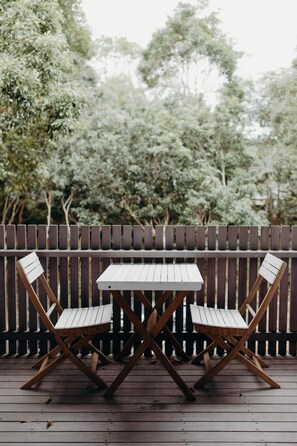 Eine Holzterrasse mit Tisch und zwei Stühlen.