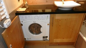 A compact kitchen with a built-in washer and dryer, wooden cabinets, and a sink.