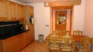 A kitchen with wooden cabinets, a black countertop, and a dining table with chairs.