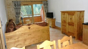 A wooden bedroom with a bed, a TV, and a cabinet.