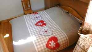 A bed with a checkered bedspread and decorative heart pillows.