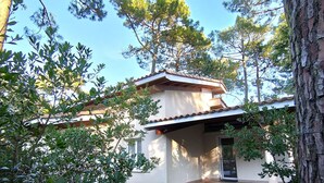 Ein modernes Haus mit Ziegeldach, umgeben von Bäumen und einem gepflegten Rasen.
