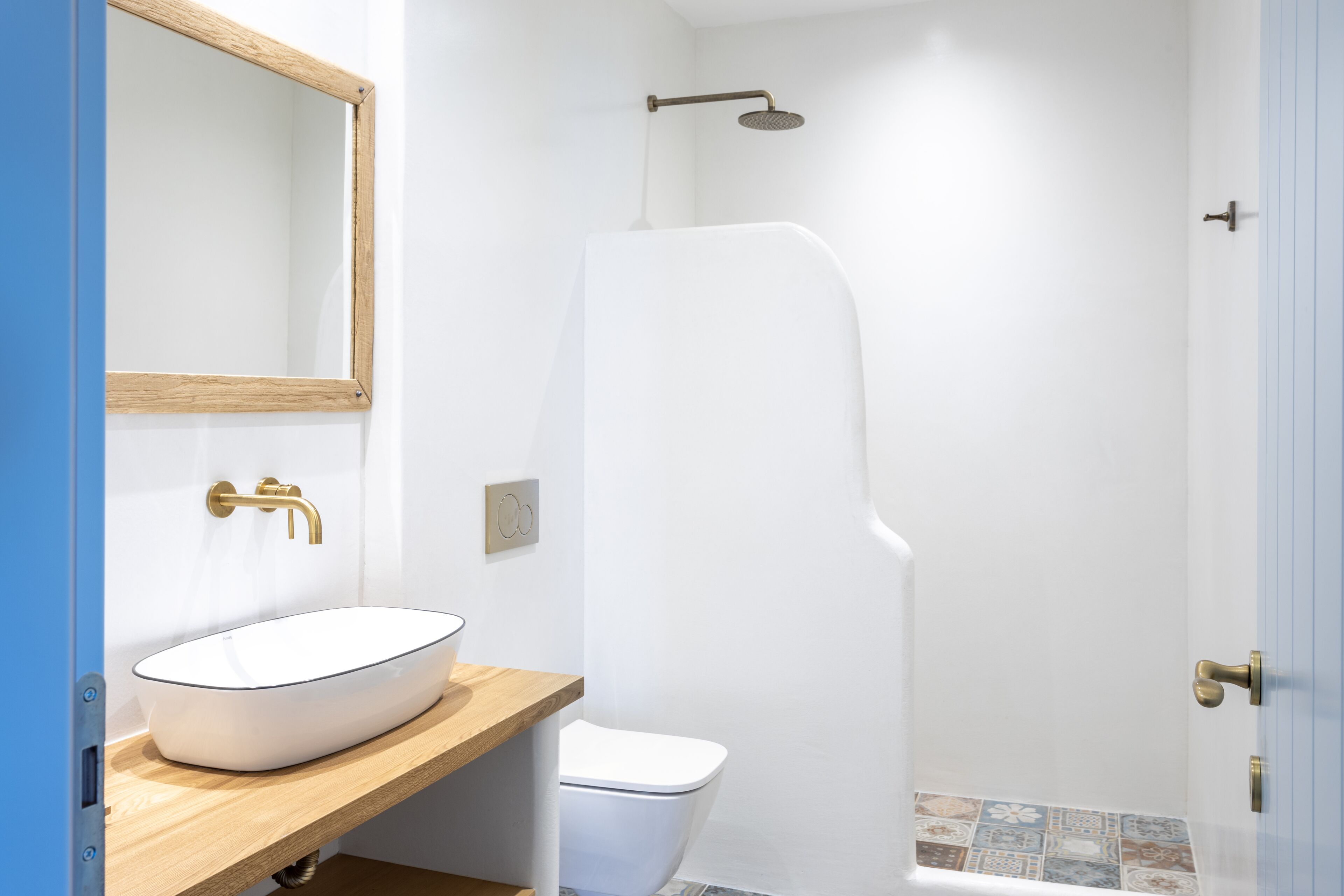 A bathroom with a white sink, a wooden countertop, a white toilet, and a shower enclosure.