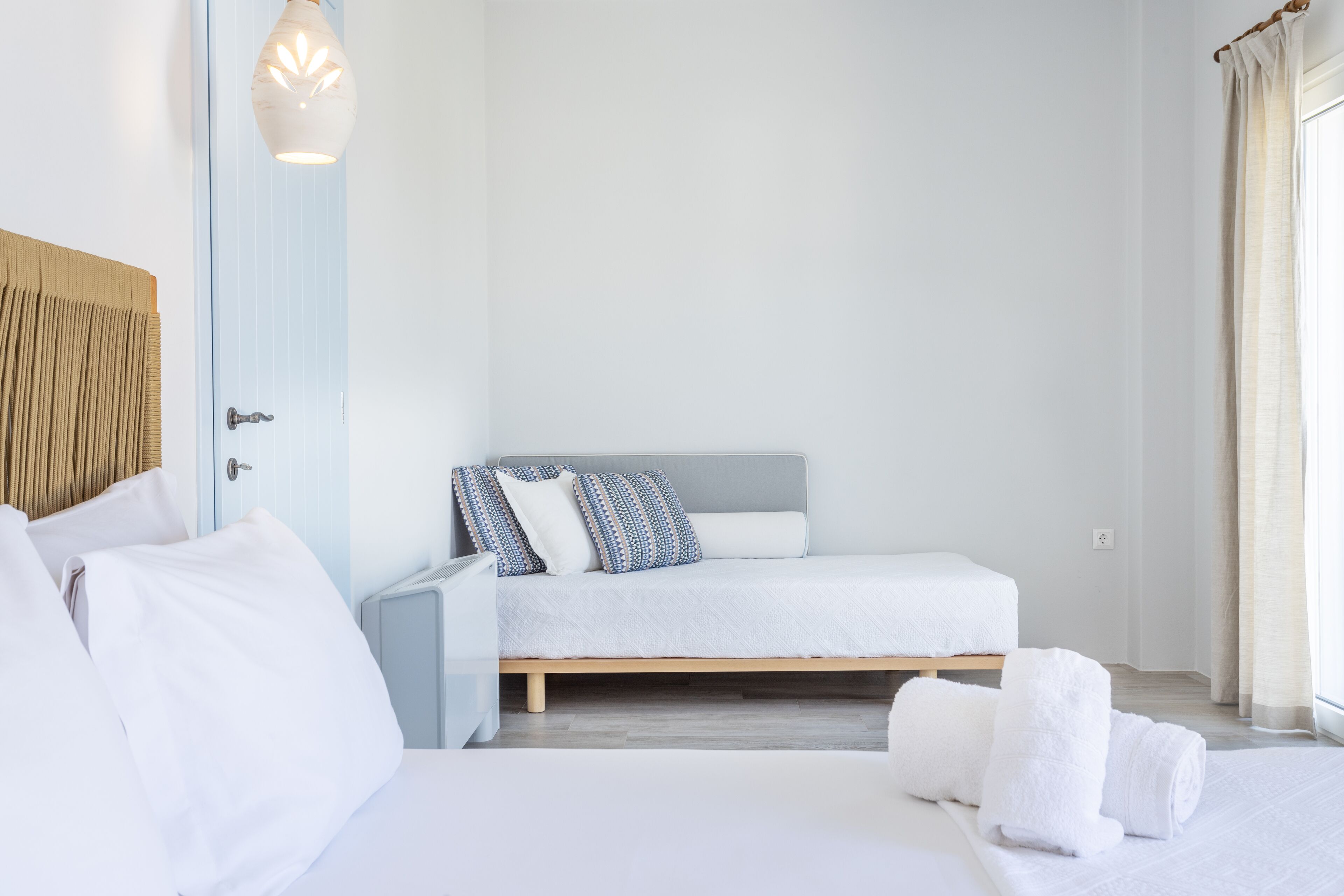 Un dormitorio con cama, almohadas, una mesita de noche y una lámpara.