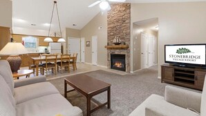 Un salon avec une cheminée, un coin repas et un téléviseur diffusant des images du « Stonebridge Village Resort ».