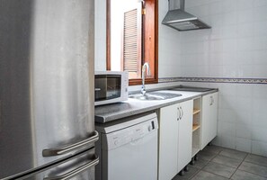 Una cocina con refrigerador de acero inoxidable, microondas, pileta y lavavajillas.
