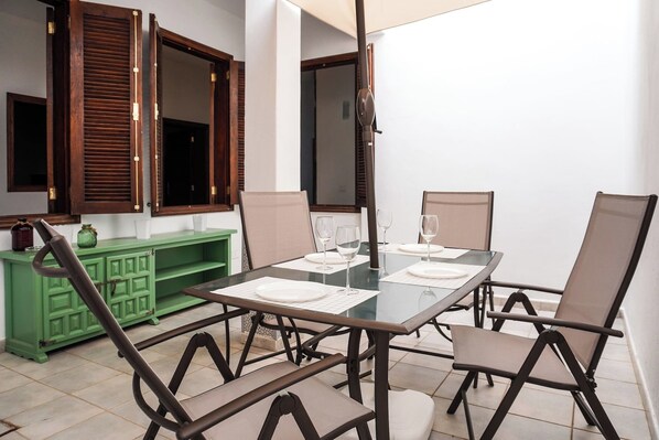 Un'area pranzo con un tavolo in vetro, sedie in metallo e un armadietto verde.