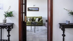 Une pièce avec un canapé vert, une petite table ronde et un tableau encadré accroché au mur.