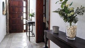 Un couloir avec une porte en bois, une petite table sur laquelle est posé un vase, et une plante en pot.