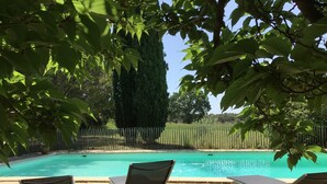 Zona de piscina con tres sillas reclinables y un patio empedrado.