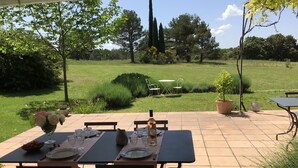 Un patio exterior con una mesa dispuesta para comer, rodeado de follaje y árboles.