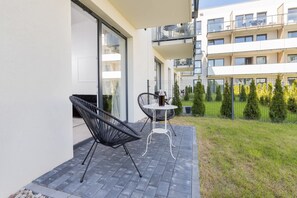 A modern apartment with a balcony featuring two black chairs and a small table.